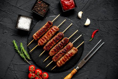 Baharatlı ızgara sosis ve siyah granit tabakta otlar.