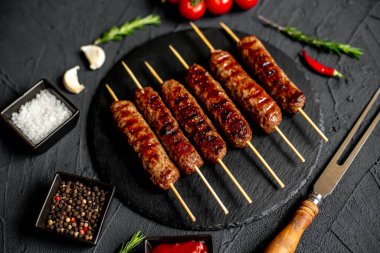 Baharatlı ızgara sosis ve siyah granit tabakta otlar.