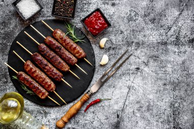 Baharatlı ızgara sosis ve siyah granit tabakta otlar.