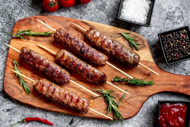 grilled sausages with rosemary and spices on a wooden background