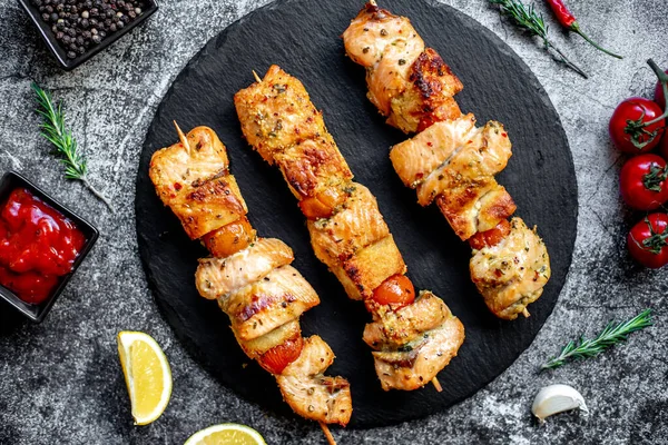 stock image grilled chicken on skewers with vegetables and spices on a black stone background