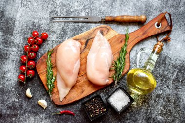 Siyah taş arka planda iki çiğ tavuk göğsü.