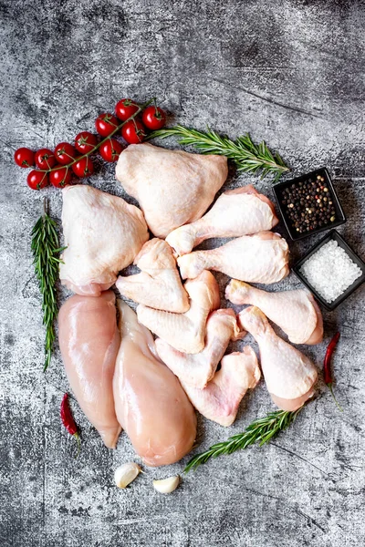 stock image Set of raw chicken fillets, thighs, wings and legs on a stone background, top view 