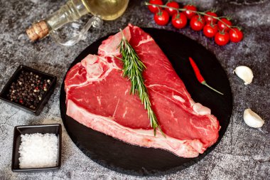 Siyah taş tahtada baharatlı ve otlu çiğ biftek.