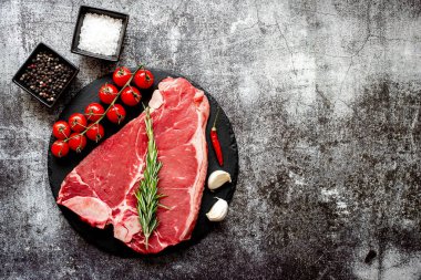 Baharatlı çiğ biftek ve taş zeminde otlar.