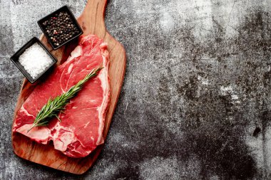 Baharatlı çiğ biftek ve taş zeminde otlar.