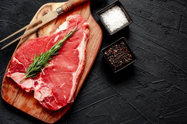 Siyah arka planda baharatlı ve otlu çiğ biftek, kopyalama alanı
