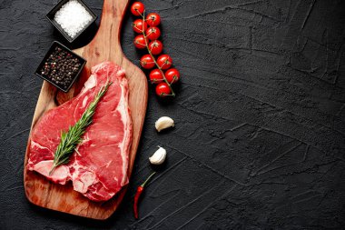 Siyah arka planda baharatlı ve otlu çiğ biftek, kopyalama alanı
