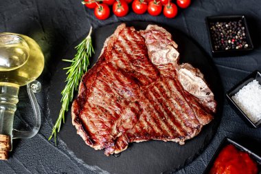 Baharatlı çiğ biftek ve siyah arka planda otlar.