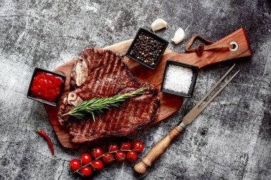 Baharatlı ızgara biftek ve ahşap tahtada biberiye.