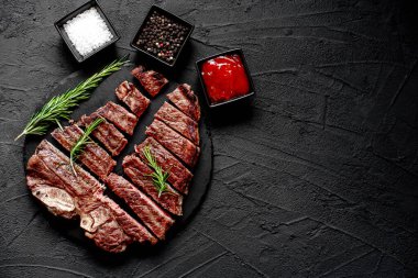 Baharatlı ızgara biftek ve siyah arka planda doğranmış biberiye, kopyalama alanı