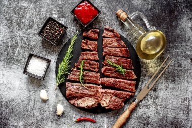Baharatlı ızgara biftek ve siyah taş tahtada doğranmış biberiye.