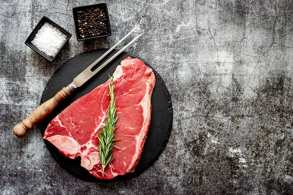 黒石板にスパイスとハーブの入った生牛ステーキ — ストック写真