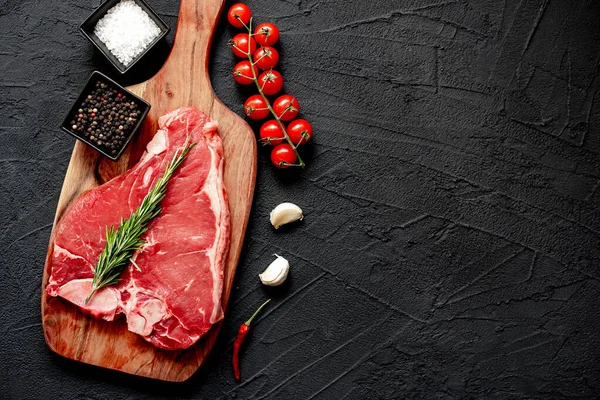 Siyah arka planda baharatlı ve otlu çiğ biftek, kopyalama alanı