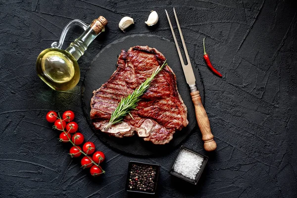 Baharatlı çiğ biftek ve siyah arka planda otlar.