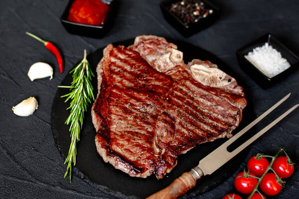 Стейк на гриле из говядины со специями и розмарином на черном фоне
