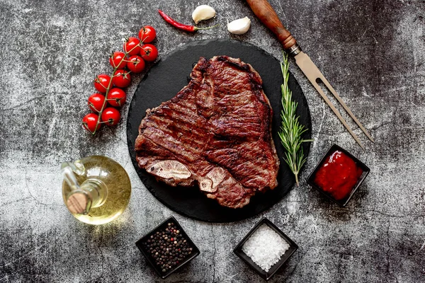 烤牛肉牛排与迷迭香和香料在黑色石板上 顶部视图 — 图库照片