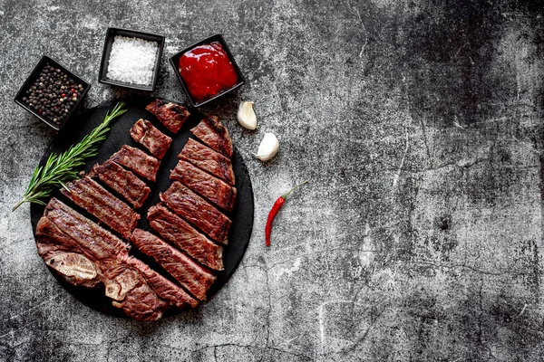 Baharatlı ızgara biftek ve siyah taş tahtada doğranmış biberiye, kopyalama alanı.