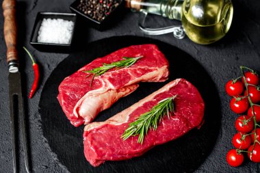 Baharatlı çiğ biftek ve siyah taş arka planda otlar.