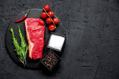 Baharatlı çiğ biftek ve siyah taş arka planda otlar.