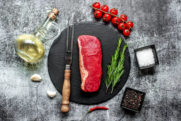 黒石の背景にスパイスとハーブの入った生牛ステーキ — ストック写真