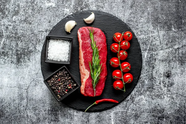 stock image raw beef steak with spices and herbs on black stone background