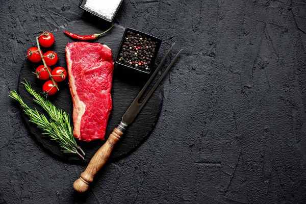 黒石の背景にスパイスとハーブの入った生牛ステーキ — ストック写真