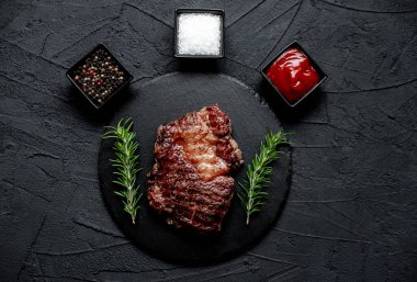 Siyah arka planda baharatlı ızgara biftek.