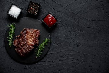 Siyah arka planda baharatlı ızgara biftek.