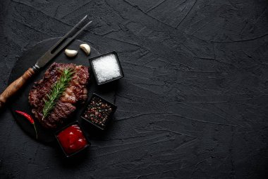 Siyah arka planda baharatlı ızgara biftek.