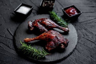 grilled chicken legs with spices and herbs on black background