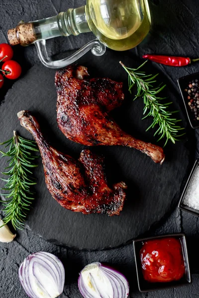 grilled chicken legs with spices and herbs on black background