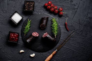 Siyah arka planda baharatlı çiğ sosis.