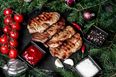 Arkaplanda Noel süslemeleri olan ızgara domuz bifteği.