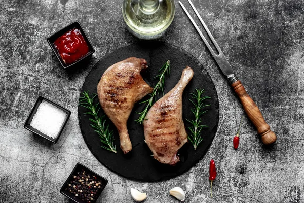 grilled ducks legs with herbs and spices on stone background
