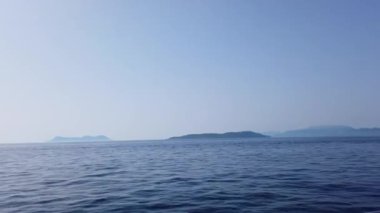 Uzaktaki Yunan adalarına giden turist teknesi, Azure sularının ve ada manzarasının manzarasını görebilir.. 