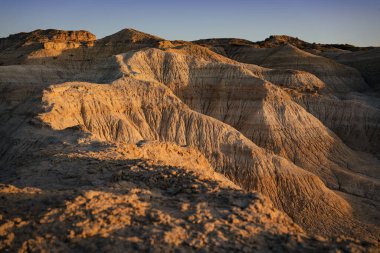 Altın saat boyunca Valle de la Luna 'daki çorak uçurum, yarı çölde kurak bir çöl manzarası jeolojik oluşumları vuruyor. General Roca, Rio Negro, Arjantin.