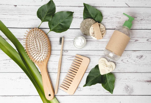 Sıfır atık banyo aksesuarlarının üst görüntüsü. Saç fırçası, tarak, diş fırçası, şampuan barı, vücut losyonu ve organik sabun. Çevre dostu ve sürdürülebilirlik kavramı