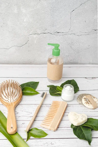 Sıfır atık kişisel bakım seti ahşap saç fırçası, tarak, diş fırçası, cam şişe, organik sabun, şampuan barı ve losyon. Sürdürülebilirlik ve güzellik kozmetik kavramı
