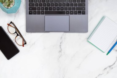 Dizüstü bilgisayarı, not defteri, cep telefonu, bilgisayar faresi, not defteri ve gözlüğü olan modern mermer bir masaüstü. Boşluğu metin için ortaya kopyala. Küçük işletme ve girişimci konsepti