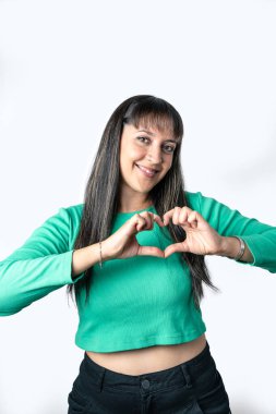 Young woman making a heart shape with her hands, isolated on white background. Vertical shot with copy space above