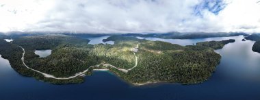 Panoramik hava manzarası, bulutlu bir gökyüzünün altında yemyeşil ormanlarla çevrili birbirine bağlı gölleri gösteriyor. Patagonya manzarası