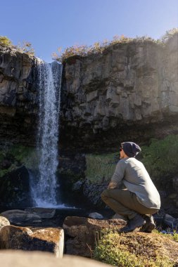 Bere takmış turist Cascada de la Usina şelalesine hayran kayalık uçurumlarda. Caviahue, Neuquen, Arjantin