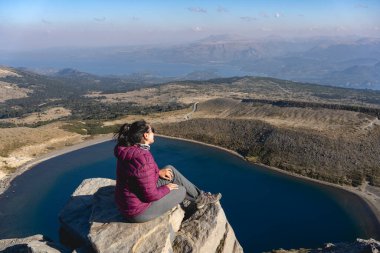 Batea Mahuida 'dan manzaranın keyfini çıkaran kadın manzarası Alumine Gölü' nü ve açık bir gökyüzünün altındaki manzarayı gösteriyor. Villa Pehuenia, Neuquen, Arjantin