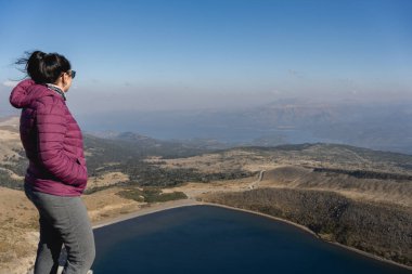 Kadın Batea Mahuida Gölü 'ne ve çevresindeki manzaraya yüksek bir perspektiften bakıyor. Villa Pehuenia, Neuquen, Arjantin