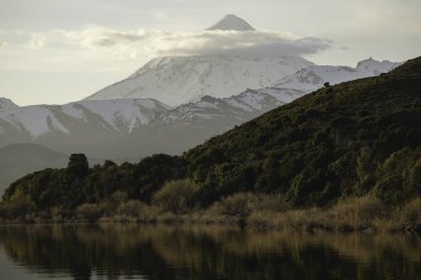 Kar, Lanin yanardağını gölün kıyısında altın bir güneşin doğuşuyla kapladı.