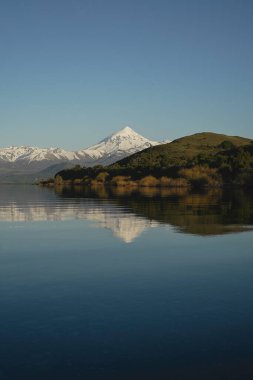Huechulafquen Gölü 'nün sakin sularına yansıyan karlı tepeli Lanin volkanı. Patagonya, Arjantin