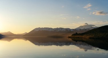 Karla kaplı dağlar ve sakin su gölüyle görkemli bir altın saat. Lanin Ulusal Parkı, Patagonya Arjantin