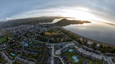 Güneş batarken Villarrica Gölü ve volkan manzaralı Pucon şehrinin hava panoramik manzarası.