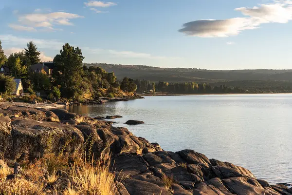 Villa Peheunia, Neuquen, Patagonya, Arjantin 'de bulutlu bir gökyüzünün altında ormanlık tepeleri olan sakin bir göl kıyısında.